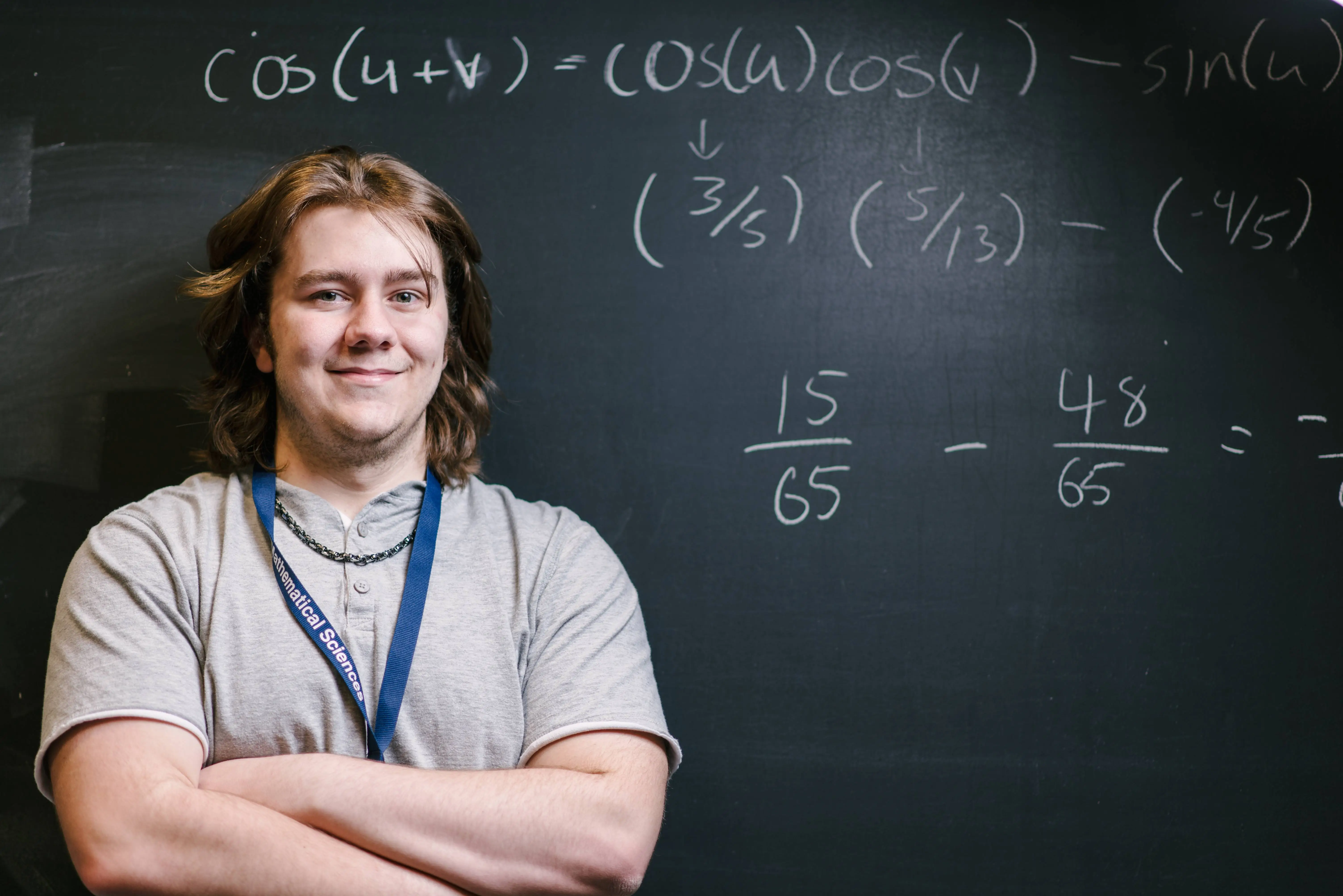 Student smiling in front of black board