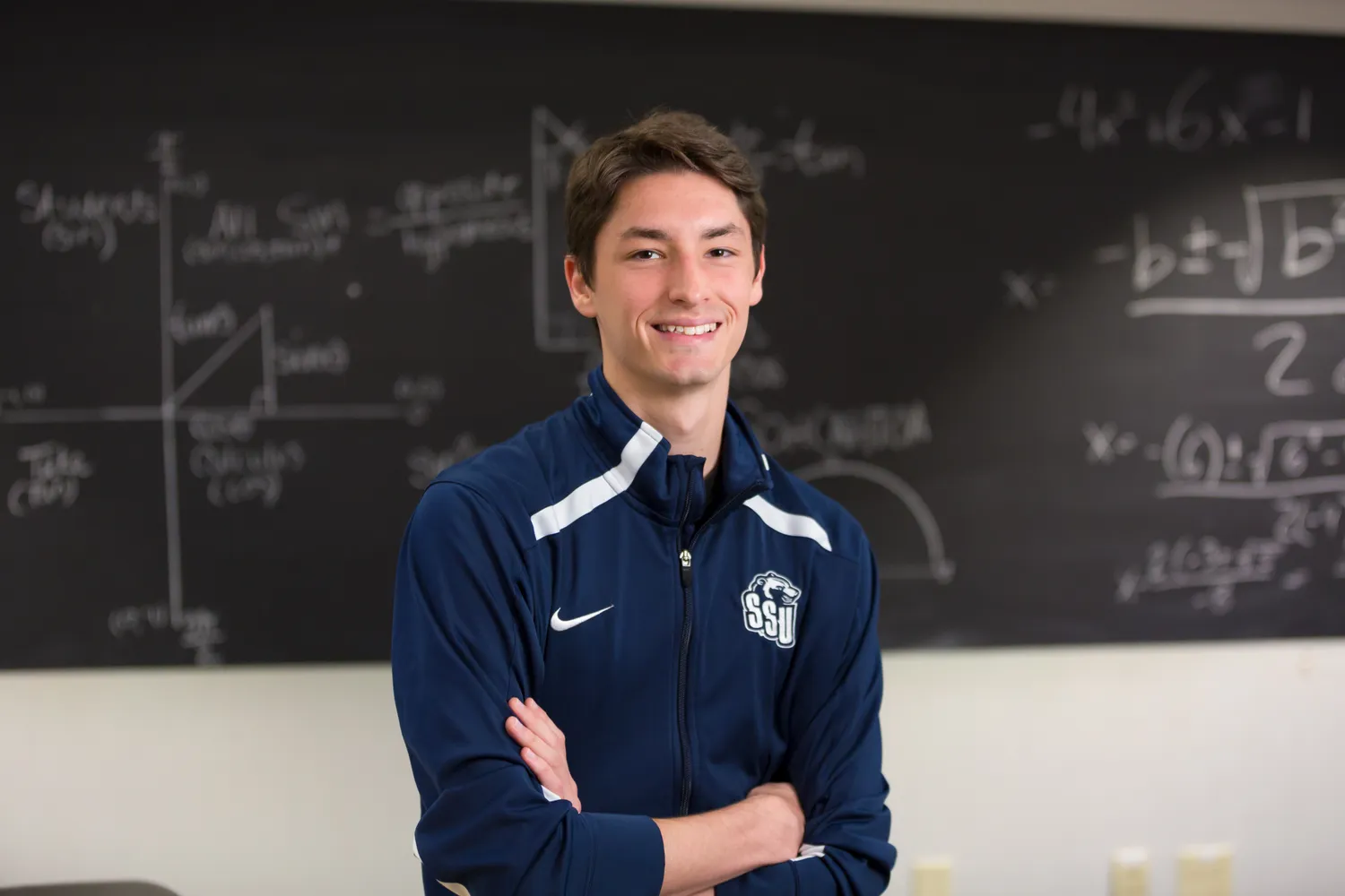 Student standing in front of a chalkboard