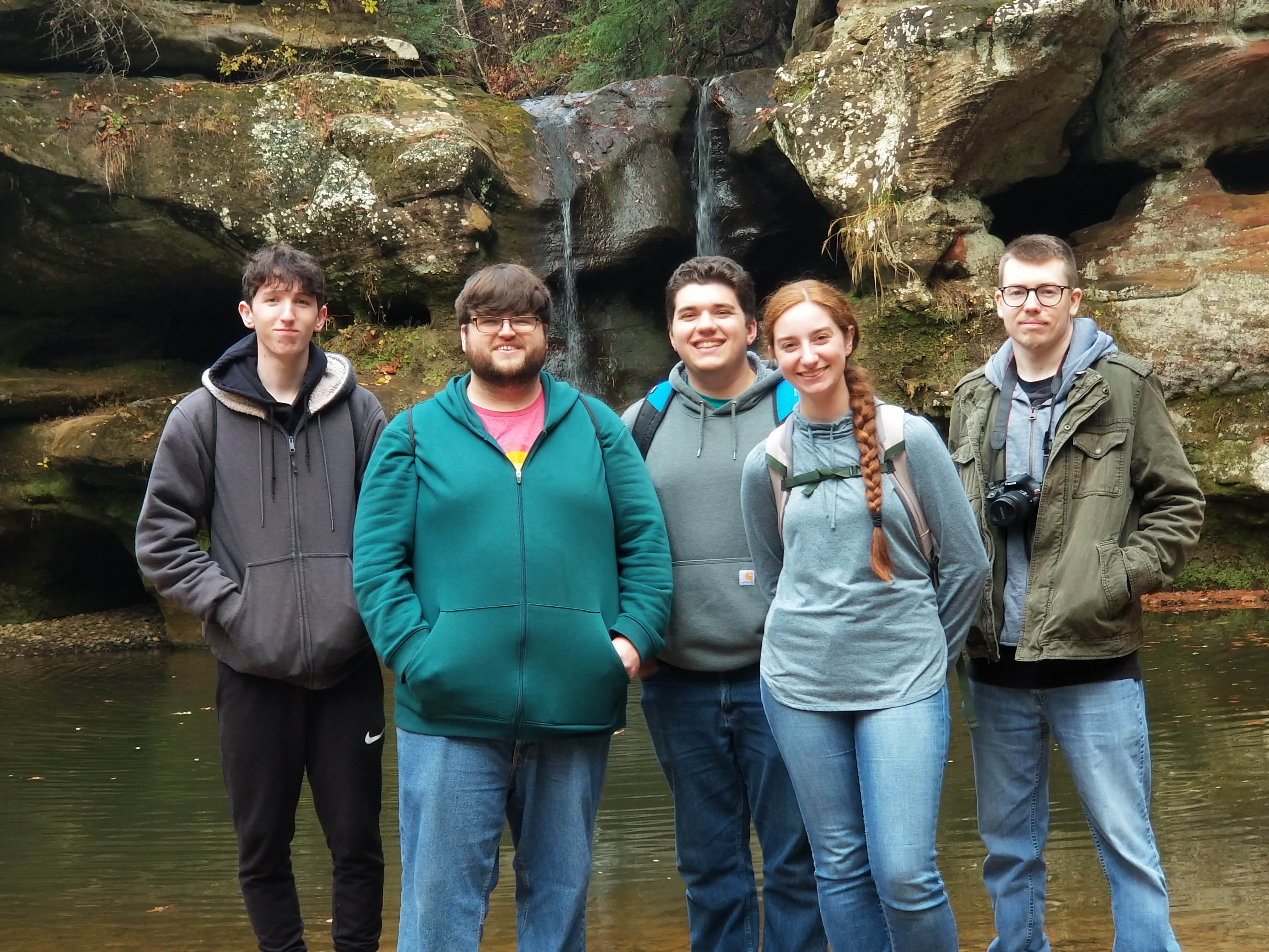 Outdoor Adventure Club standing in front of waterfall on group hike.