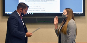 photo of man reciting oath and young woman raising right hand